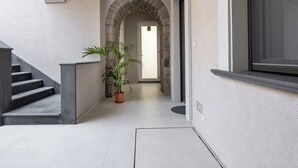 Un interior moderno con un arco de piedra que conduce a una puerta, una planta en maceta y una escalera.