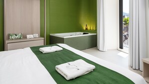 Una habitación de hotel moderna con una cama grande, una bañera y un balcón con vistas.