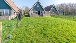 A row of three houses with a grassy yard in between. - Tastefully and Modernly Furnished Holiday Home for 6 Persons (De Waal)