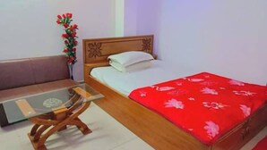Un dormitorio con cama de madera, una mesita de madera y una colcha roja con estampado floral.