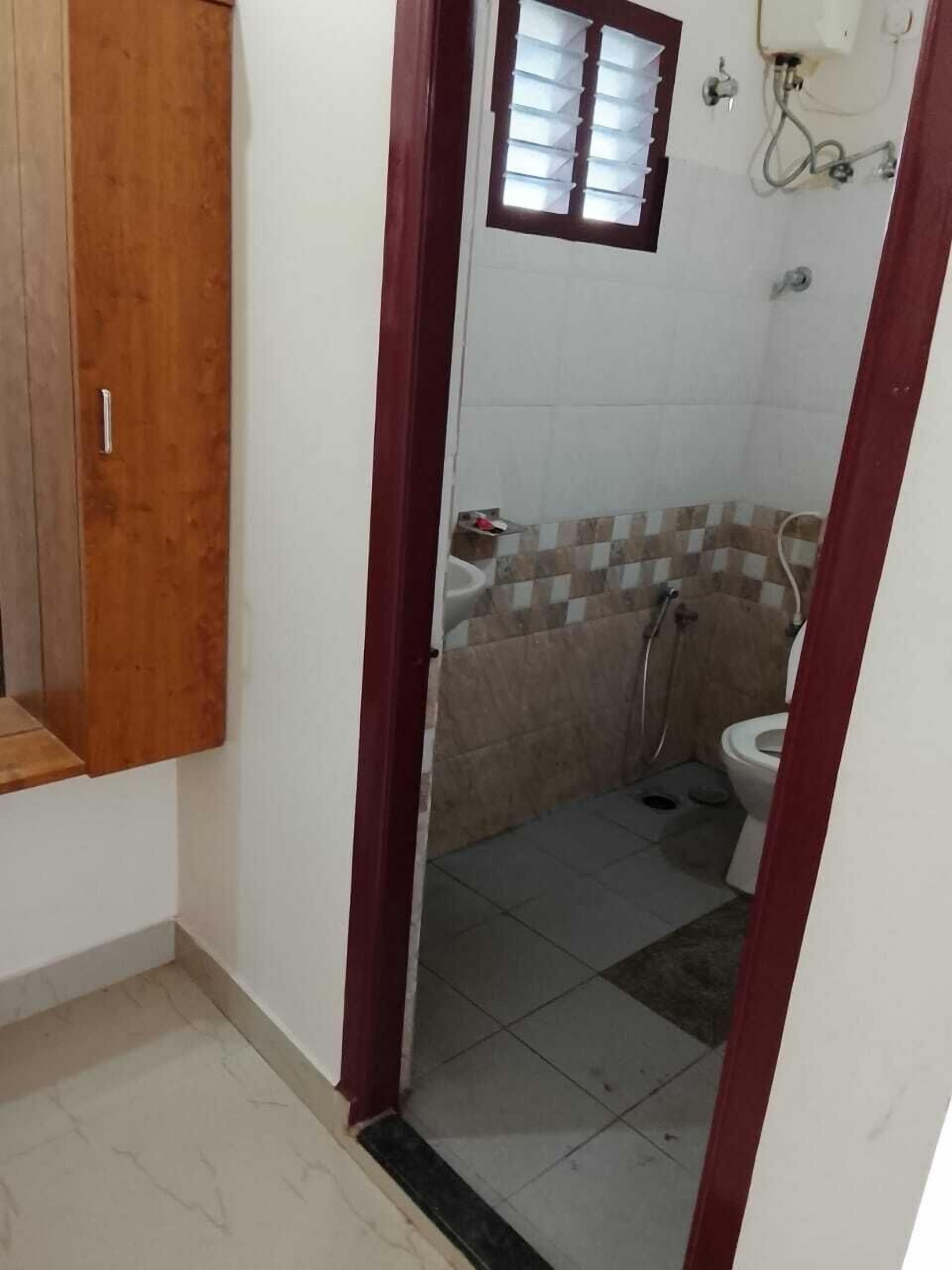 Un baño pequeño con inodoro, ducha y lavamanos. Cuenta con un armario de madera y una ventana con persianas.