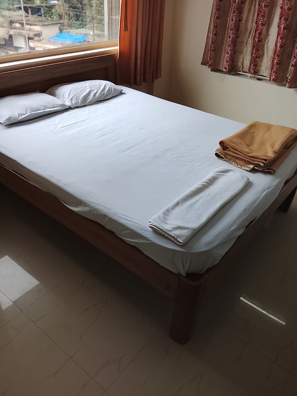 Una cama individual con ropa blanca, una toalla doblada y una colcha al lado derecho.