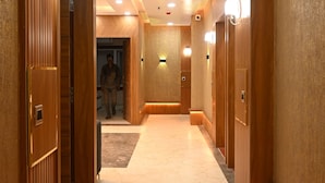 A hallway with wooden doors, recessed lighting, and a marble floor. - Hotel KIR International (Awleshpur)