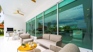Un salon moderne comprenant un canapé, des fauteuils, une table basse et un espace barbecue.
