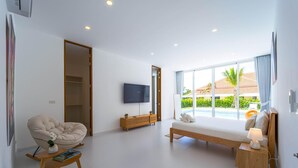 Une chambre d’hôtel moderne dotée d’une grande fenêtre, d’un téléviseur à écran plat, d’un canapé, d’un banc en bois et d’une petite table agrémentée d’une plante.