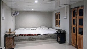 Un dormitorio con cama, una mesita, un ventilador y una ventana.