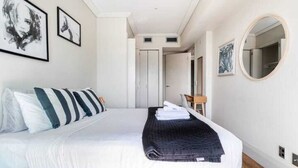 A modern hotel room with a large bed, a flat-screen TV, and a small desk area. - Waterfront Nest Above Viaduct Harbour Free Parking (Auckland)