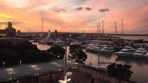A marina at sunset with boats docked and a cityscape in the background. - Waterfront Nest Above Viaduct Harbour Free Parking (Auckland)