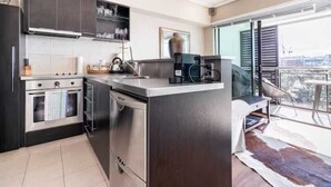 A modern kitchen with dark cabinetry, stainless steel appliances, and a large island. - Waterfront Nest Above Viaduct Harbour Free Parking (Auckland)