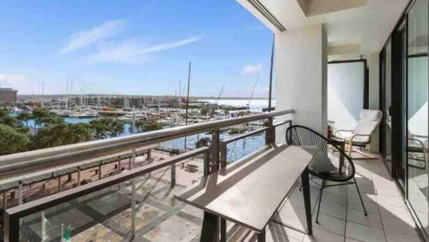 A balcony with a view of a marina, a table, and two chairs. - Waterfront Nest Above Viaduct Harbour Free Parking (Auckland)