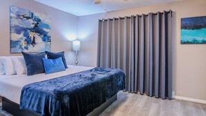 Une chambre à coucher comprenant un lit, un ventilateur de plafond, une table de chevet et une lampe fixée au mur.