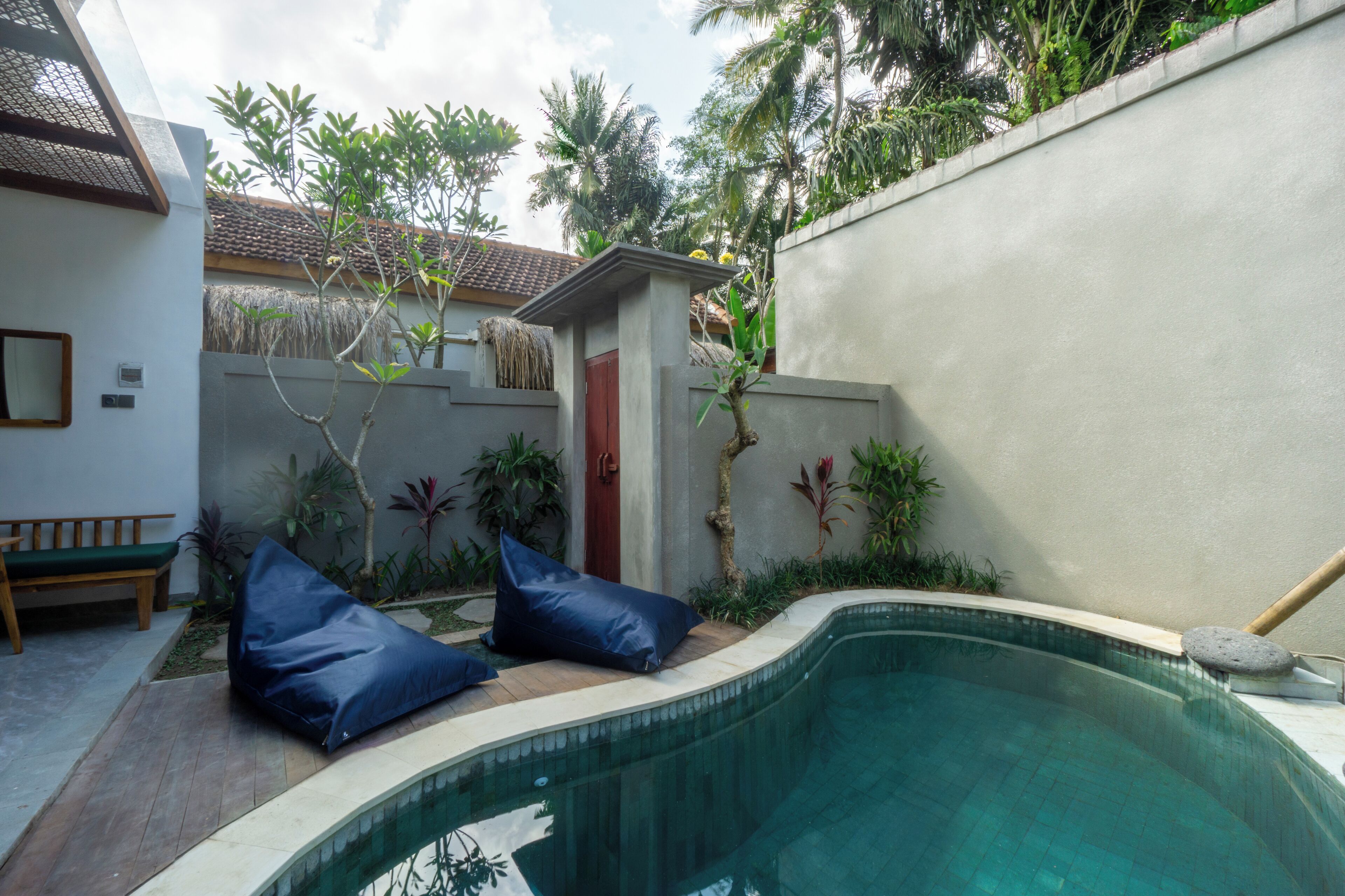 A swimming pool with a curved edge, surrounded by a low wall and a bench.