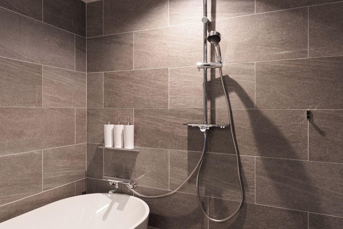 Een moderne badkamer met een vrijstaand bad, een handdouche en een handdoekrek.