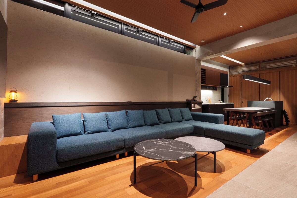 A modern living room with a sectional sofa, two round coffee tables, and a kitchen area in the background.