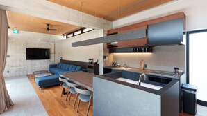 Una cocina moderna con una isla central, electrodomésticos integrados y un comedor con sofá y sillas.