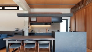 Una cocina moderna con una isla central, electrodomésticos integrados y una zona de comedor con sofá y sillas.