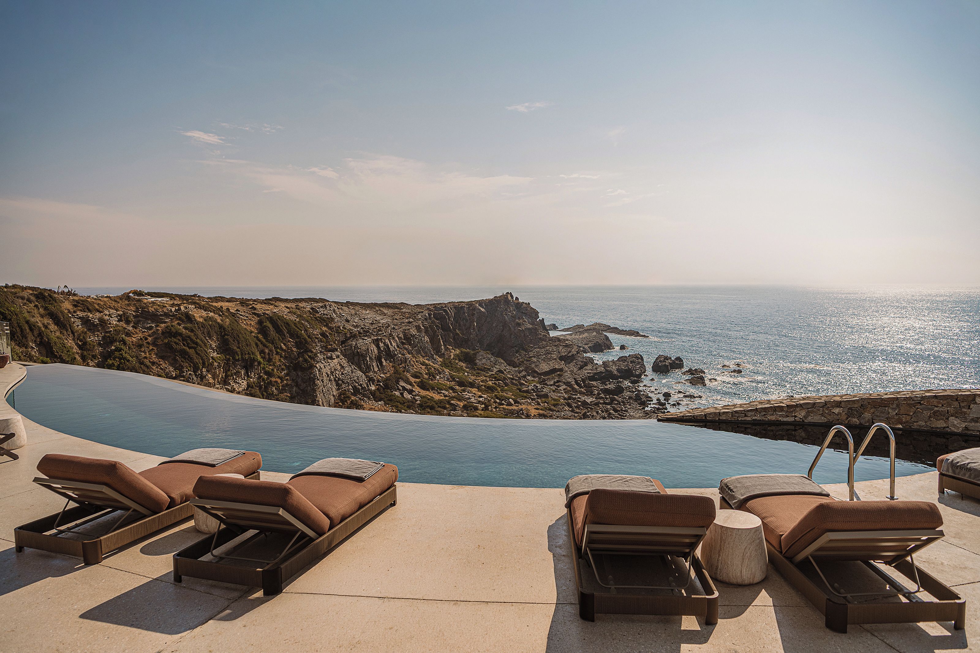 A poolside area with lounge chairs and a view of the sea.