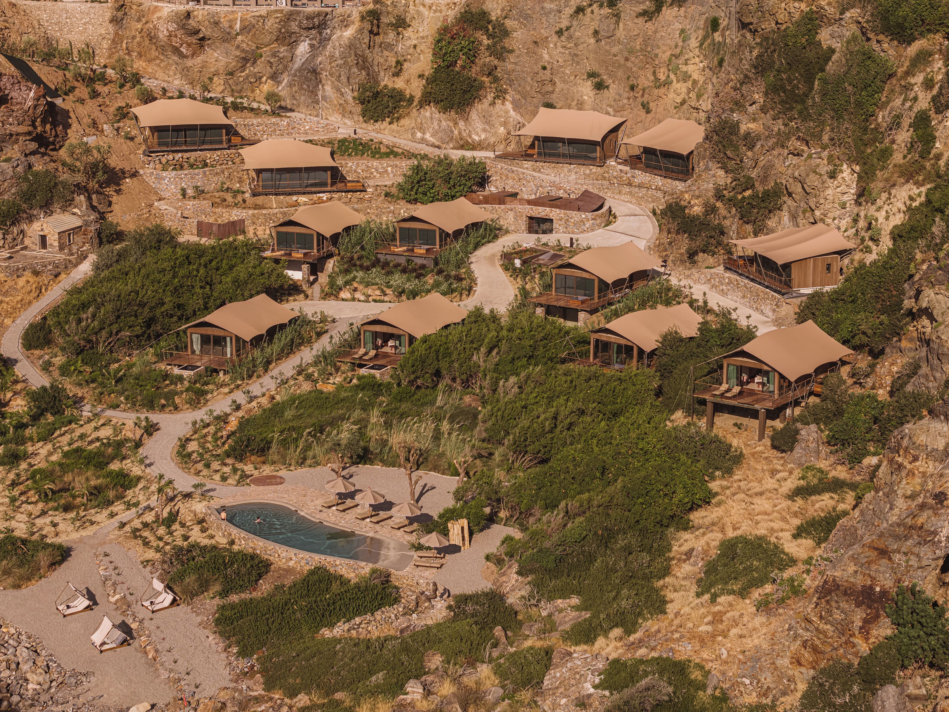 A cluster of modern, tent-like structures with a pool and outdoor seating area.