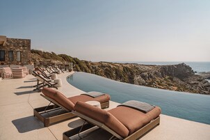A poolside lounge area with sun loungers and a view of the ocean.