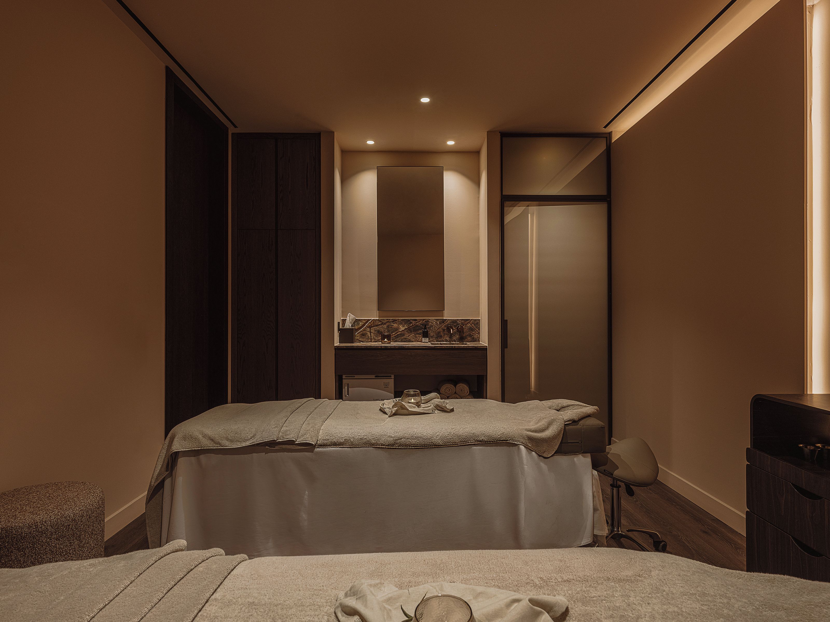 A hotel room with a bed, a vanity with a mirror, and a wardrobe.