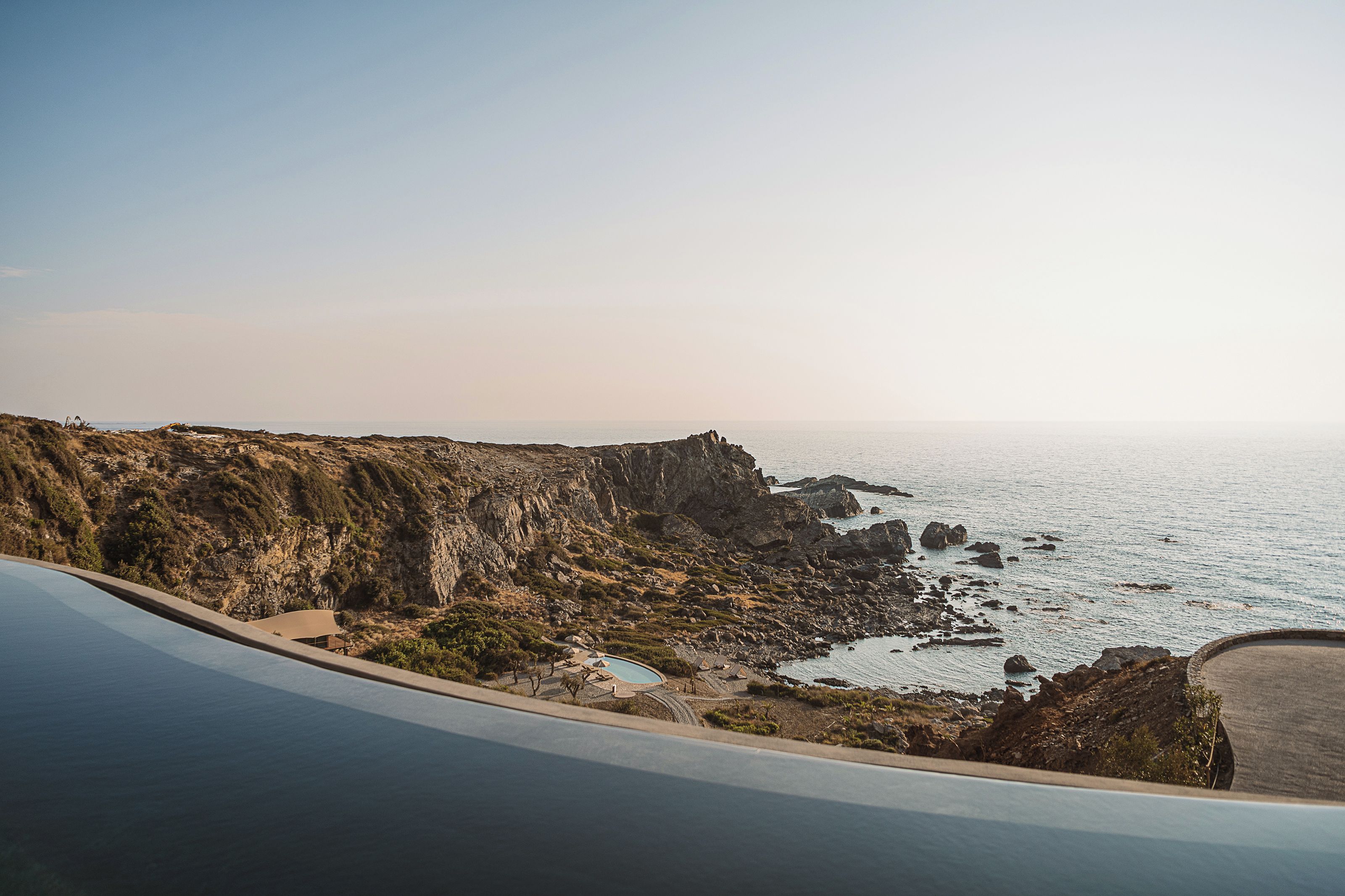 A coastal road with a rocky cliff and a clear view of the sea.