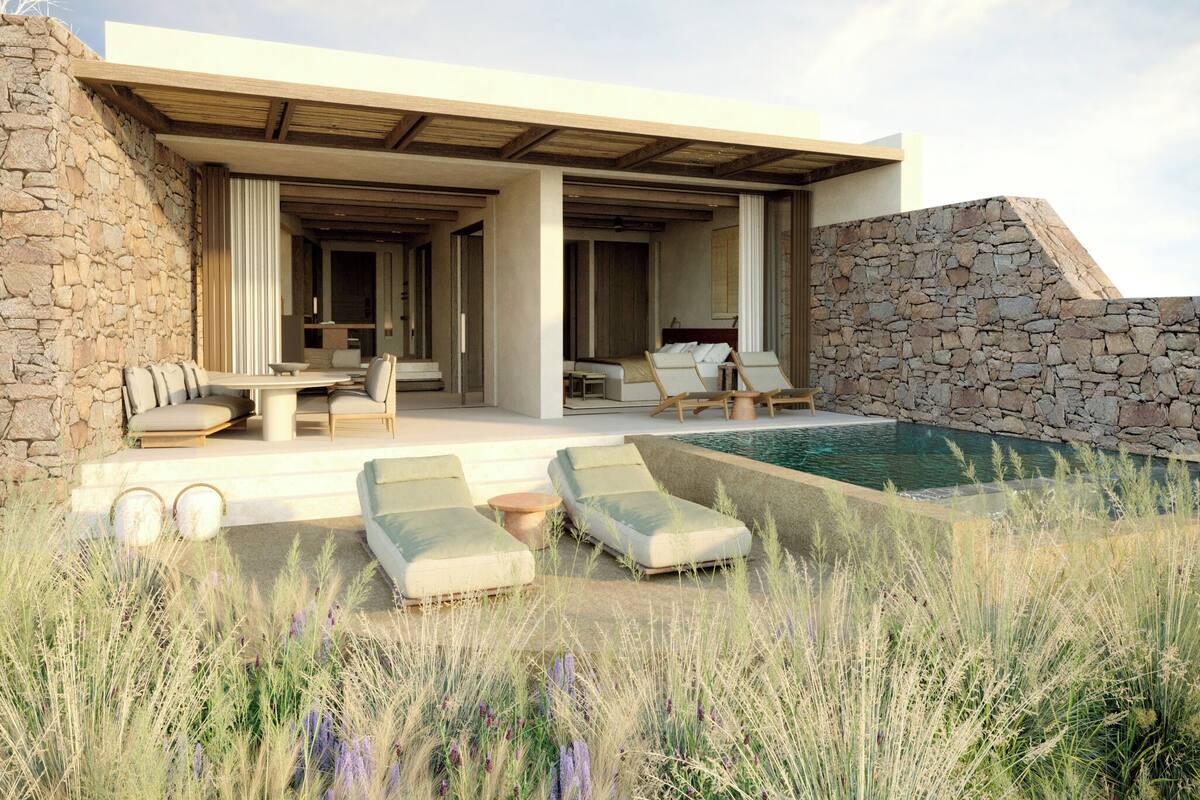 A modern outdoor living area with a pool, stone walls, and lounge chairs.
