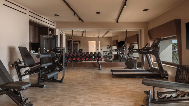 Ett gym med träningsutrustning, en spegel och ett fönster.