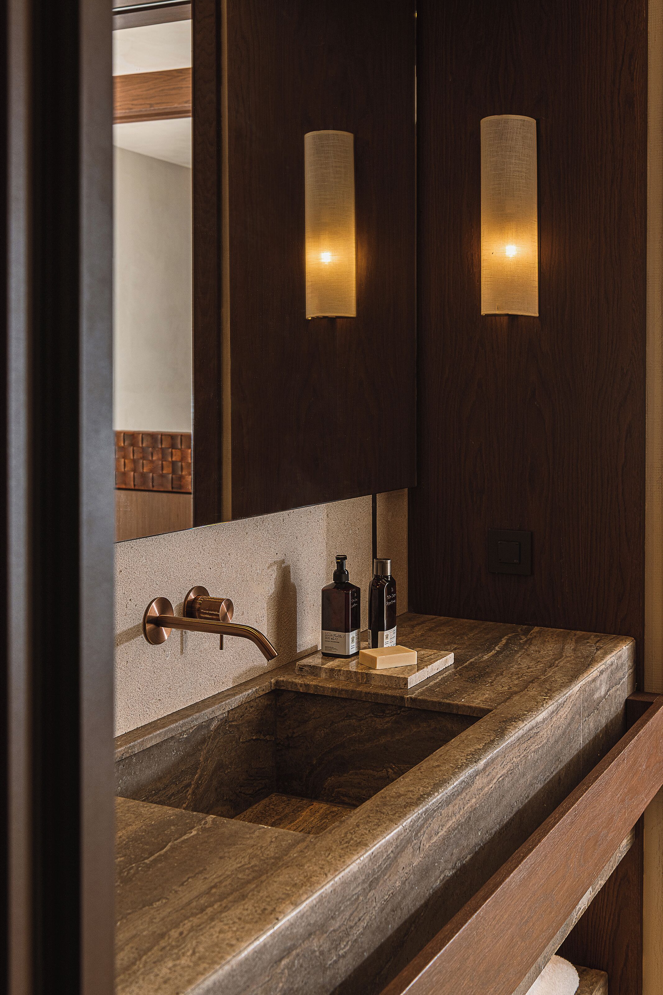 A bathroom with a wooden vanity, a sink, and two wall-mounted lights.