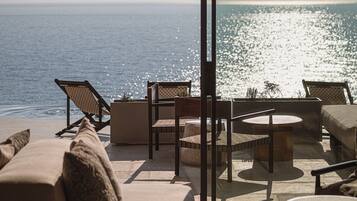 Ein Balkon mit Meerblick, ausgestattet mit einer Couch, Stühlen und einem Tisch.