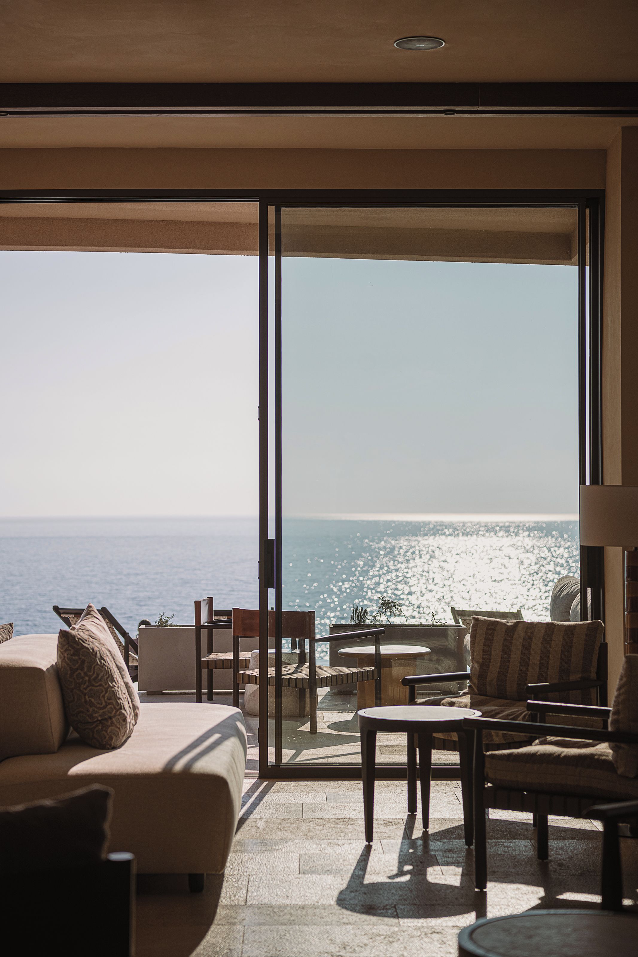 A room with a large sliding glass door leading to a balcony overlooking the sea.
