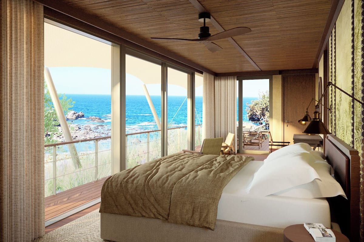 A bedroom with a large bed, a ceiling fan, and a view of the sea.