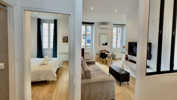 A modern apartment with a bedroom, living area, dining space, and a TV.