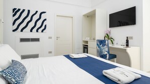Una habitación de hotel con cama, escritorio, televisión, espejo y puerta.