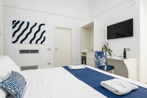 Ein Hotelzimmer mit Bett, Schreibtisch, Fernseher, Spiegel und Tür.