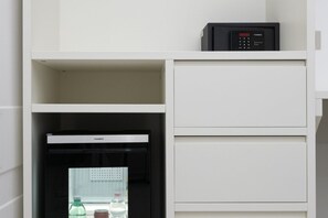 Un mini-bar blanc avec un réfrigérateur noir et un panneau de commande sur le dessus.