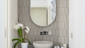 Een badkamer met een wit wastafelmeubel, een spiegel en een potorkidee.