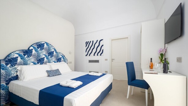 Un dormitorio con una cama, un escritorio, una silla y un televisor.