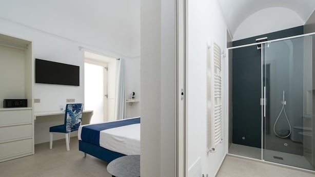 Een moderne slaapkamer met een bed, bureau, stoel en een inloopkast.