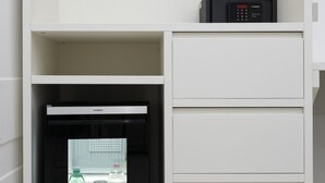 Een witte minibar met een zwarte koelkast en een bedieningspaneel bovenop.