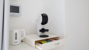 Een koffieapparaat, een digitale klok en een lade met koffiepads.