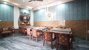 A dining area with a long table, chairs, and a ceiling fan. - NOVA RESORTS (Raebareli)