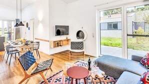 Ett modernt vardagsrum med en matplats, stora fönster och utsikt över omgivningen.