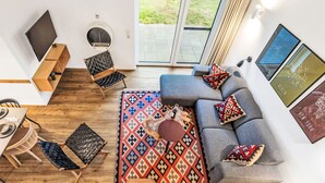 Ett modernt vardagsrum med en grå soffa, ett mönstrat matt och en matplats med ett bord och stolar.