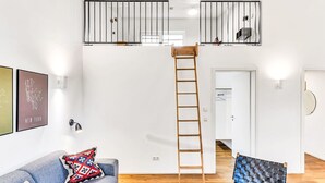 En lägenhet i loftstil med en trappa, en soffa, ett soffbord och en stol.