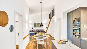 Ett modernt kök med en inbyggd ugn och en matplats med ett träbord och stolar.
