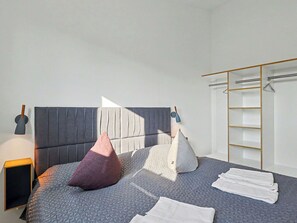 A modern bedroom with a bed, pillows, a nightstand, a lamp, and a wardrobe. - Beautiful private villa for 8 guests with WIFI, TV and terrace (Diepholz)