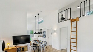 A modern apartment with a living room, dining area, and kitchen. There is a TV, a wooden ladder, and a sofa. - Wonderful private villa for 8 people with WIFI, TV and terrace (Diepholz)