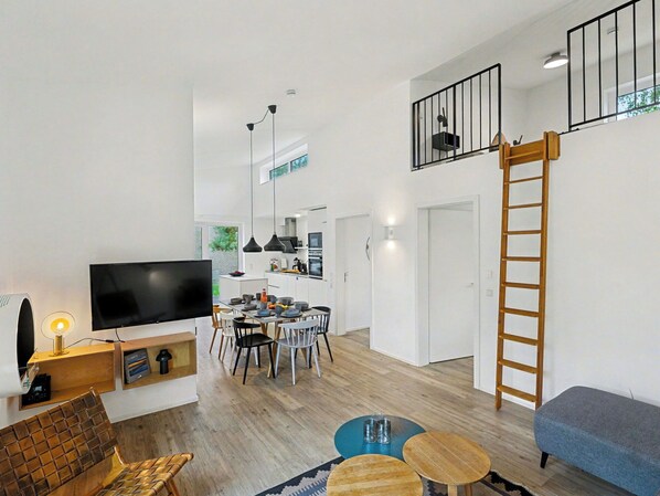 A modern living room with a flat-screen TV, a wooden coffee table, and a blue sofa. - Beautiful private villa for 8 guests with WIFI, TV and terrace (Diepholz)