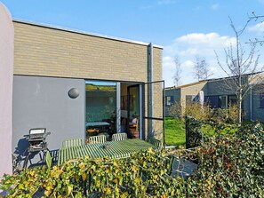 A modern building with a brick facade, a glass door entrance, and a patio area with outdoor furniture. - Beautiful private villa for 8 guests with WIFI, TV and terrace (Diepholz)
