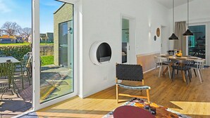 Un interior modern amb una zona de menjador, una zona d'estar i un gran finestral corredís que dona a un patí.